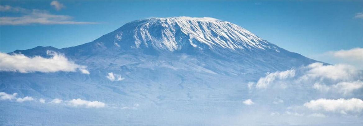 The snow-covered summit of Mount Kilimanjaro rising above the clouds